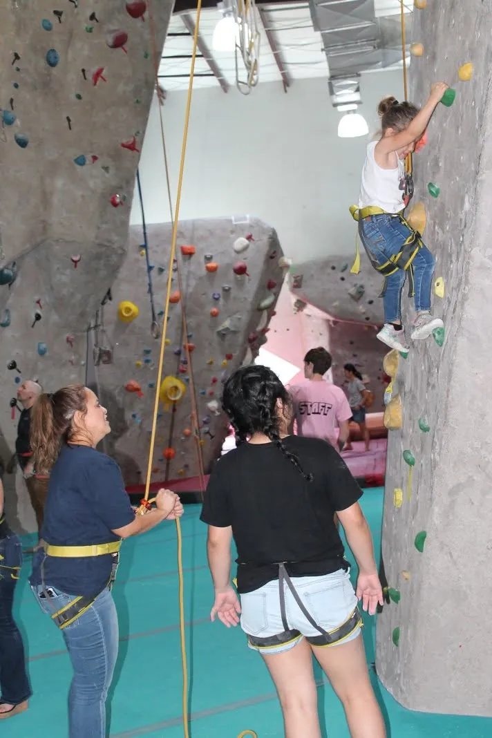 Children and adults participate in an indoor climbing activity