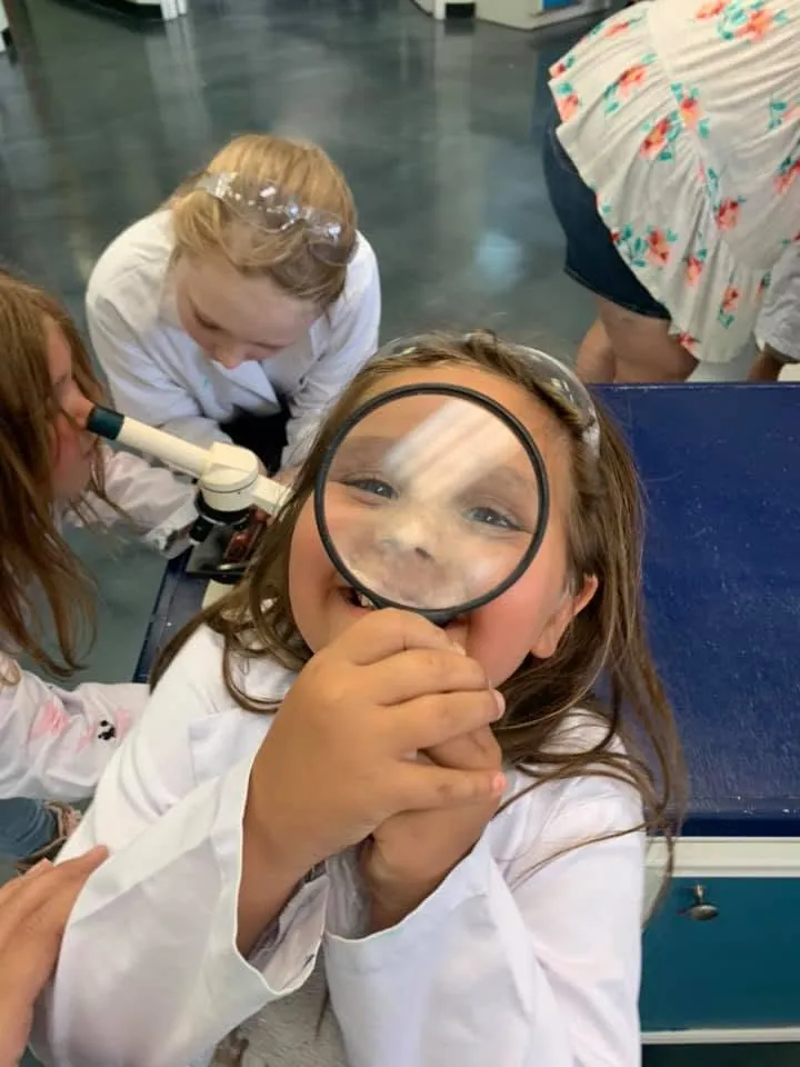 A child looks through a magnifying glass during a hands-on activity