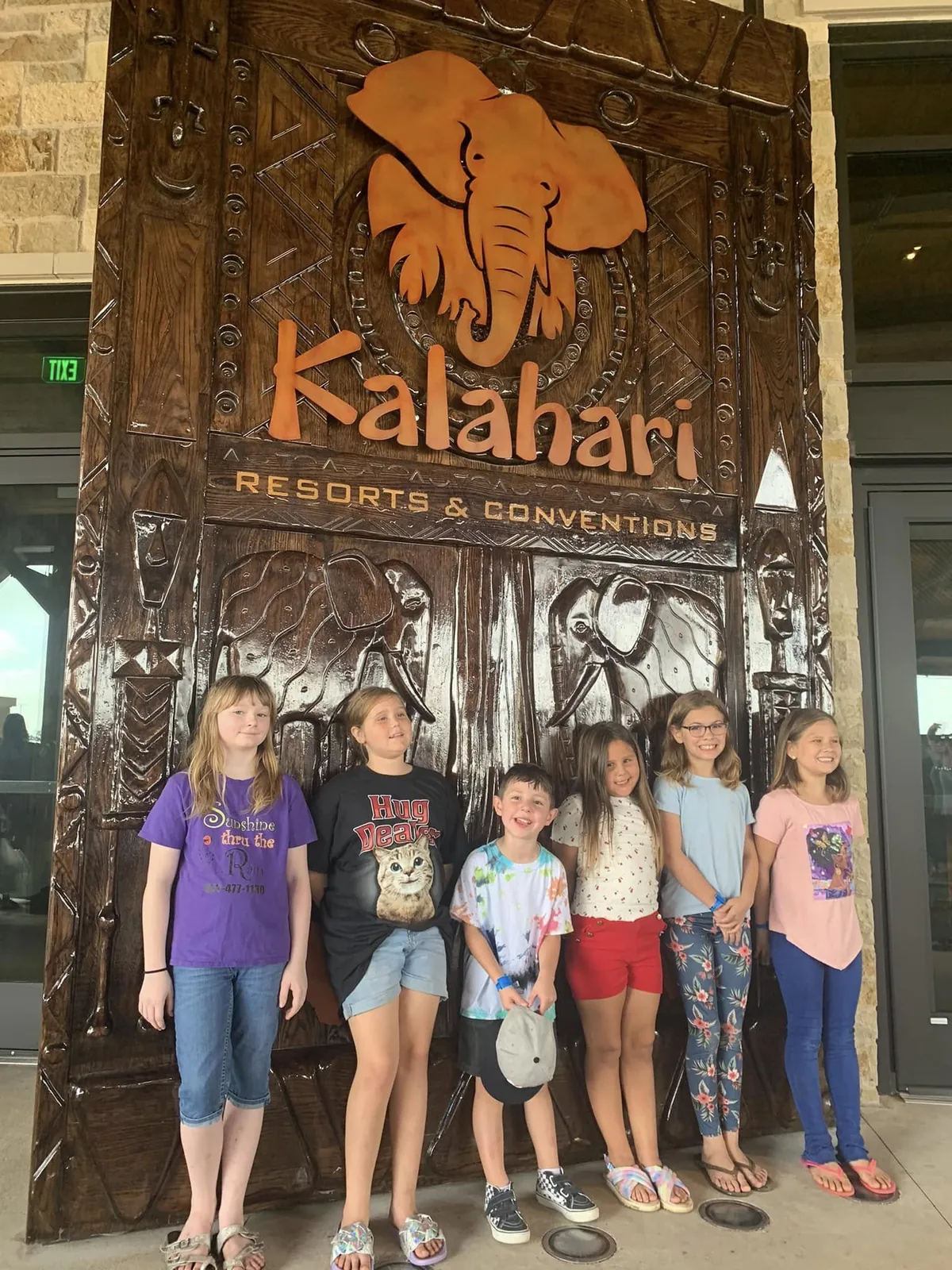Children and adults pose beside a Kalahari sign during a group outing