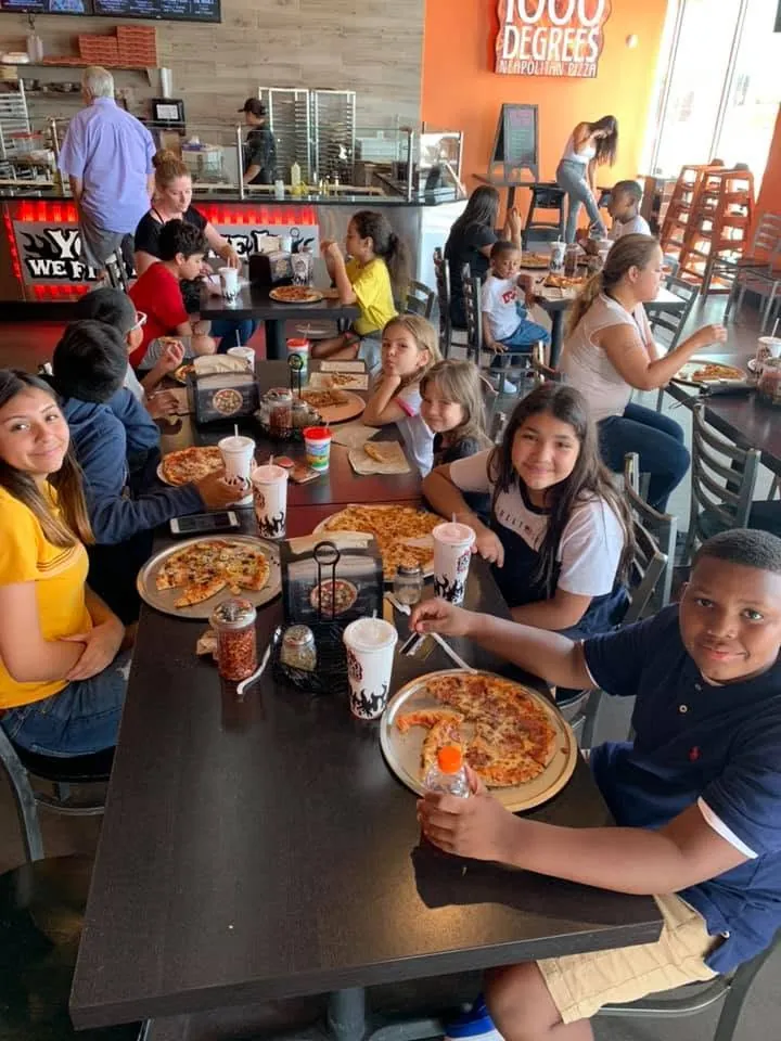 Children and adults share a meal together around a restaurant table